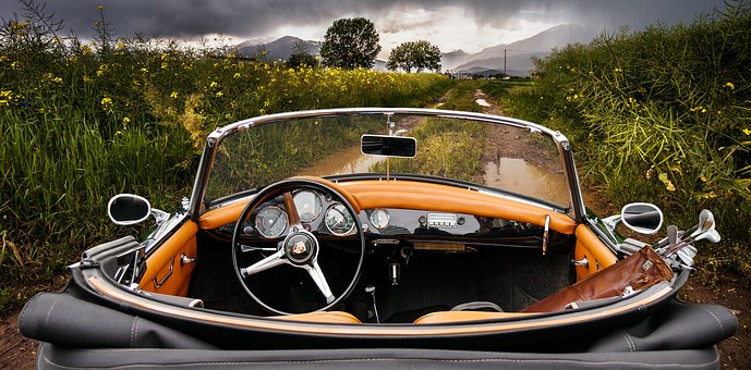 Classic convertible car on a muddy rural road on a cloudy day